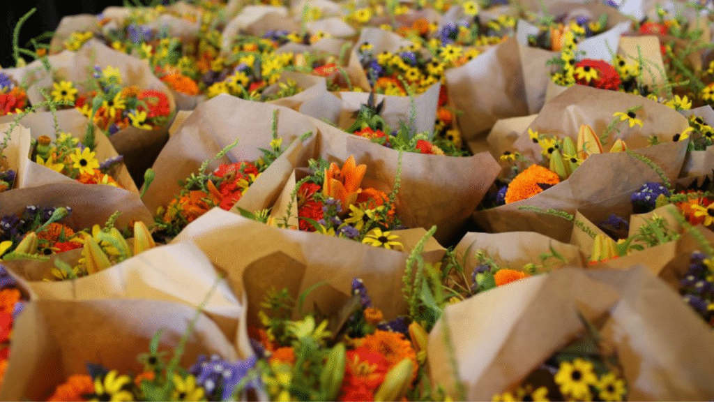 "Cut flower bouquets wrapped in paper, ready to sell at a farmer’s market or local shop"